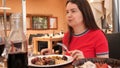 Woman sitting at table in catalan restaurant and eating traditional Spanish dish, parillada de carne.