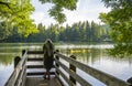 Woman enjoying lake view in forest standing on wooden pier