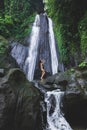 Woman enjoying near hidden in jungle cascade waterfall Dusun Kuning in Bali