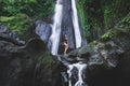 Woman enjoying near hidden in jungle cascade waterfall Dusun Kuning in Bali