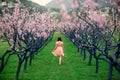 Woman enjoying spring in the green field with blooming trees