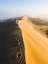 Woman enjoying sunrise on top of huge sand dune. Sahara desert, Morocco. Royalty Free Stock Photo