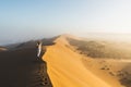 Woman enjoying sunrise on top of huge sand dune in Sahara desert, Morocco Royalty Free Stock Photo