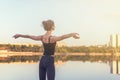 Woman enjoying sunset with arms outspread and face raised in sky