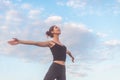 Woman enjoying sunset with arms outspread and face raised in sky
