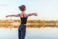 Woman enjoying sunset with arms outspread and face raised in sky