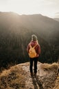 Woman enjoying the sunset in nature on the edge of a rock cliff. Woman hiker enjoys mountains view. Royalty Free Stock Photo