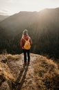 Woman enjoying the sunset in nature on the edge of a rock cliff. Woman hiker enjoys mountains view. Royalty Free Stock Photo