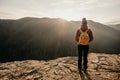 Woman enjoying the sunset in nature on the edge of a rock cliff. Woman hiker enjoys mountains view. Royalty Free Stock Photo