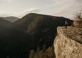 Woman enjoying the sunset in nature on the edge of a rock cliff. Woman hiker enjoys mountains view. Royalty Free Stock Photo