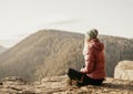 Woman enjoying the sunset in nature on the edge of a rock cliff. Woman hiker enjoys mountains view. Royalty Free Stock Photo