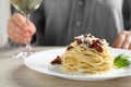 Woman enjoying tasty spaghetti with sun-dried tomatoes and parmesan cheese and wine at wooden table in restaurant, closeup. Royalty Free Stock Photo