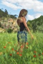 Woman enjoying a walk in a poppy field under the summer sun. Royalty Free Stock Photo