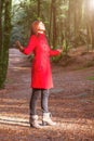 Woman enjoying the warmth of winter sunlight alone on forest park path with arms open Royalty Free Stock Photo