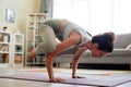 Woman enjoying yoga workout at home holding handstand balance position