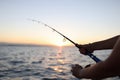 Woman enjoys fishing on boat sailing in sea at sunset Royalty Free Stock Photo