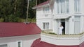 Woman enjoys morning on balcony of cottage. Video. Top view of rich woman sipping coffee on balcony of her large cottage