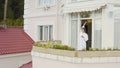 Woman enjoys morning on balcony of cottage. Video. Top view of rich woman sipping coffee on balcony of her large cottage