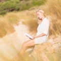 Woman enjoys reading on beautiful sandy beach. Royalty Free Stock Photo