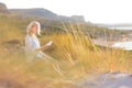 Woman enjoys reading on beautiful sandy beach. Royalty Free Stock Photo