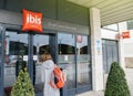Woman entering the ibis hotel entrance welcome door with red signage