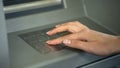Woman entering PIN number to check bank account and withdraw money from ATM