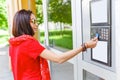 Woman at the entrance of her house touch an electronic key token at doorphone for entry, a concept of security and access Royalty Free Stock Photo