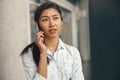 Woman entrepreneur talking phone with client while standing in office and looking at side Royalty Free Stock Photo