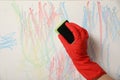 Woman erasing child`s drawing from wall, closeup