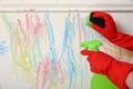 Woman erasing child`s drawing from white wall, closeup