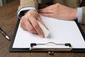 Woman erasing something on paper at wooden table, closeup