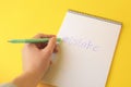 Woman erasing word Mistake written with erasable pen in notepad on yellow background, above view