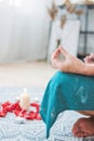 Woman in ethnic costume practicing yoga in front of candles and red rose petals, hands with mehendi Royalty Free Stock Photo