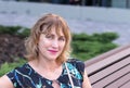 Woman, a European, middle-aged, 50-55 years old, a pretty blonde, sitting on a park bench Royalty Free Stock Photo