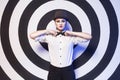 Woman with evening make up and red lips in a bow-tie in a center of a dartboard background Royalty Free Stock Photo