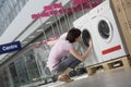 Woman Examining Front Loader Of Washing Machine