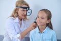 Woman examining girls ear through frontal reflector Royalty Free Stock Photo