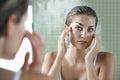 Woman Examining Herself In Front Of Mirror