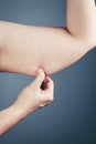 Woman with the excessive fat checking her upper arm, grey background. Royalty Free Stock Photo