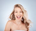 Woman, excited face or expression and blonde hair in motion on gray studio background in frizz free wavy hairstyle