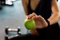 Woman exercise in gym fitness breaking and relax. hand holding apple fruit after training sport and dumbbell, water bottle on the