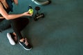 Woman exercise in gym fitness breaking and relax. hand holding apple fruit after training sport and dumbbell, water bottle on the