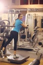 Woman exercising in gym with exercise-machine - leg day, wellbeing concept Royalty Free Stock Photo