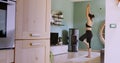 Woman exercising at home following a remote yoga class. Woman doing home relaxation with TV. Yoga Tree position