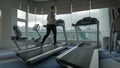 Woman exercising on running machine in front of panoramic window