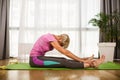Woman exercising and stretching her body doing flexibility exercises, sitting on a yoga mat indoor Royalty Free Stock Photo