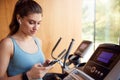 Woman Exercising On Treadmill Wearing Wireless Earphones And Smart Watch Checking Mobile Phone Royalty Free Stock Photo