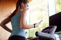 Woman Exercising On Treadmill Wearing Wireless Earphones And Smart Watch Checking Mobile Phone