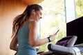 Woman Exercising On Treadmill Wearing Wireless Earphones And Smart Watch Checking Mobile Phone Royalty Free Stock Photo