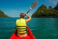 Woman exploring calm tropical bay with limestone mountains by kayak, back view Royalty Free Stock Photo